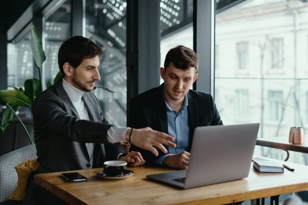 two-businessmen-pointing-laptop-screen-while-discussing-min